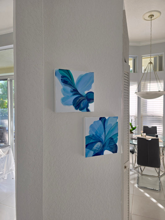 Two blue floral paintings on a white wall with a modern interior setting.