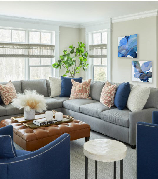 Living room with gray sectional sofa, blue and orange pillows, and a brown ottoman.